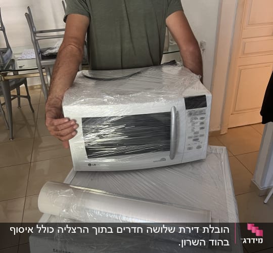 אדם נושא מיקרוגל עטוף בניילון